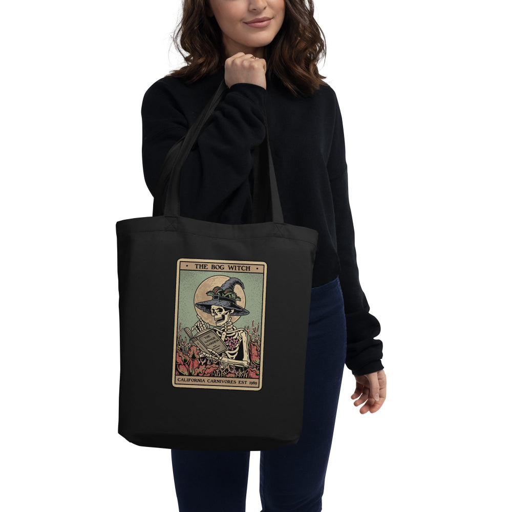Person holding a black tote bag with a graphic design on a white background