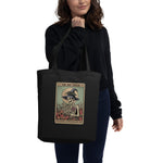 Person holding a black tote bag with a graphic design on a white background