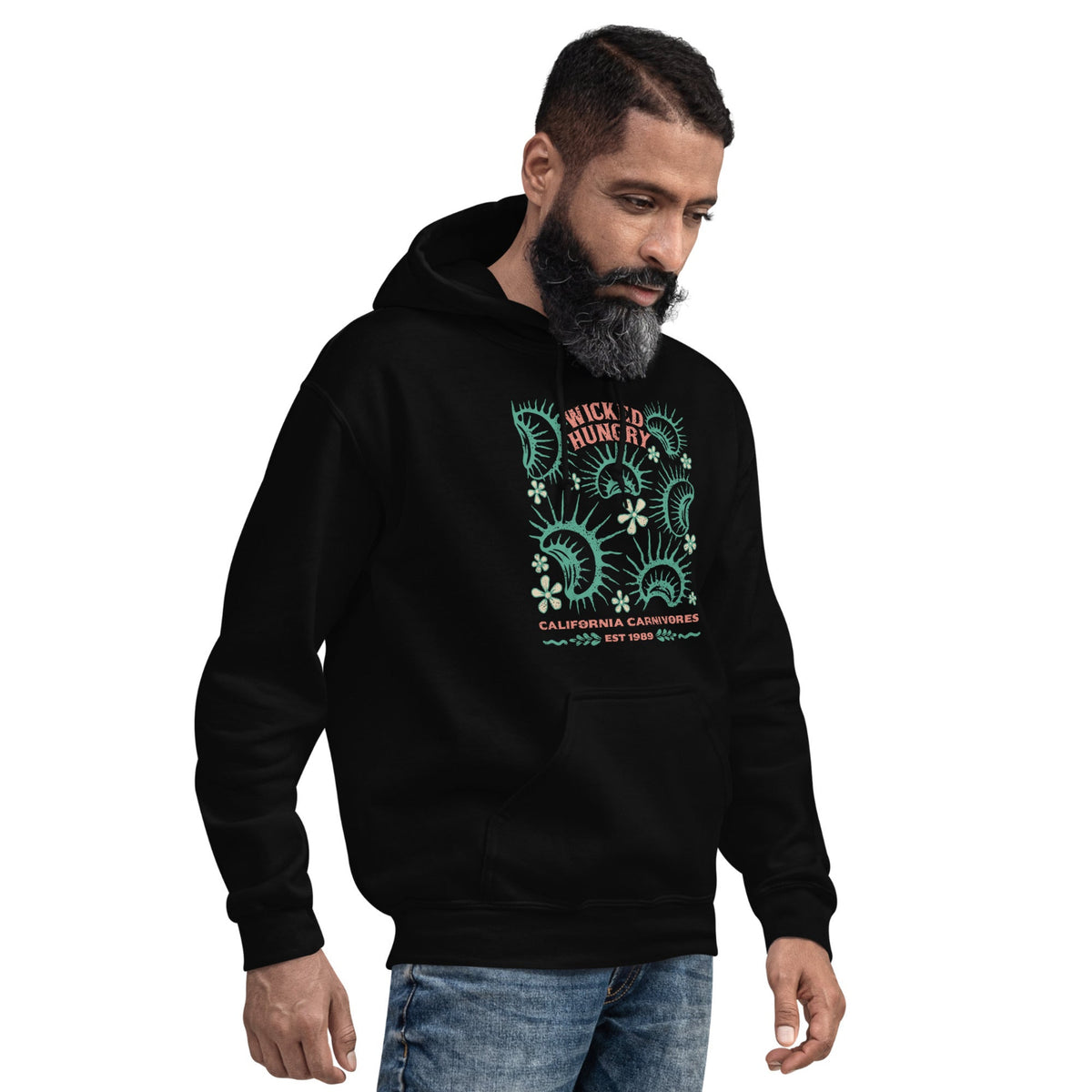 Black California Carnivores unisex hoodie with Wicked Hungry in coral, in the upper middle, surrounded by wood block print style flytraps in teal on male model