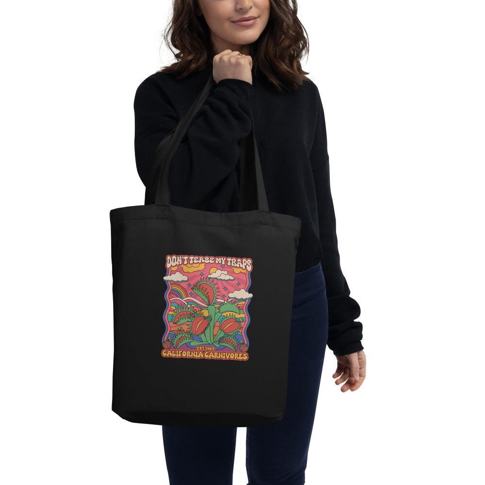 Person holding a black tote bag with colorful design and text.