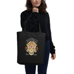 Person holding a black tote bag with a colorful skull design and text.