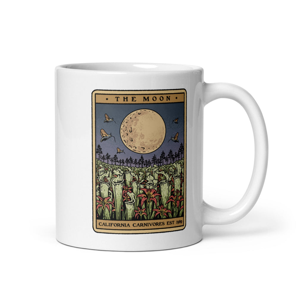 White mug with 'The Moon' tarot card design featuring a moon, trees, and animals on a white background.