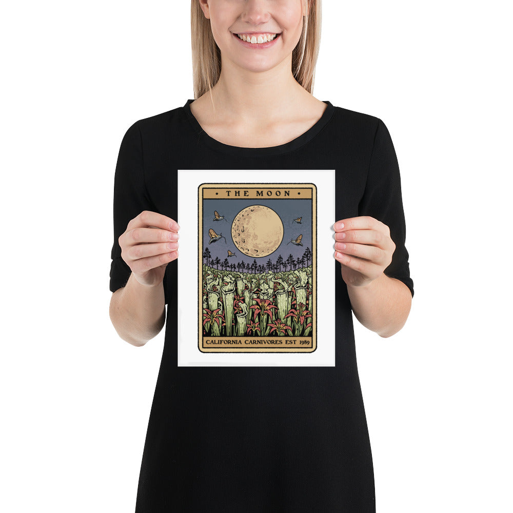 Person holding a framed print titled 'The Moon' against a white background