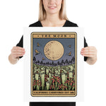 Person holding a framed artwork titled 'The Moon' by California Carnivores.