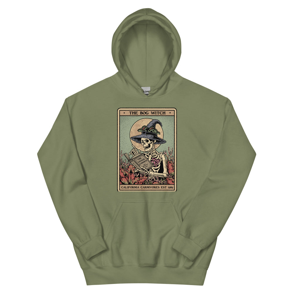 Green hoodie with a graphic design of a skeleton in a witch hat and broomstick on a white background