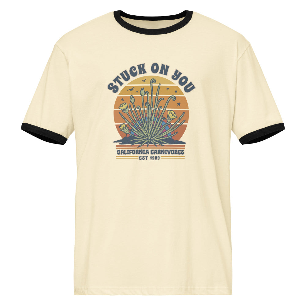 Beige t-shirt with black trim featuring a graphic design and text on a white background