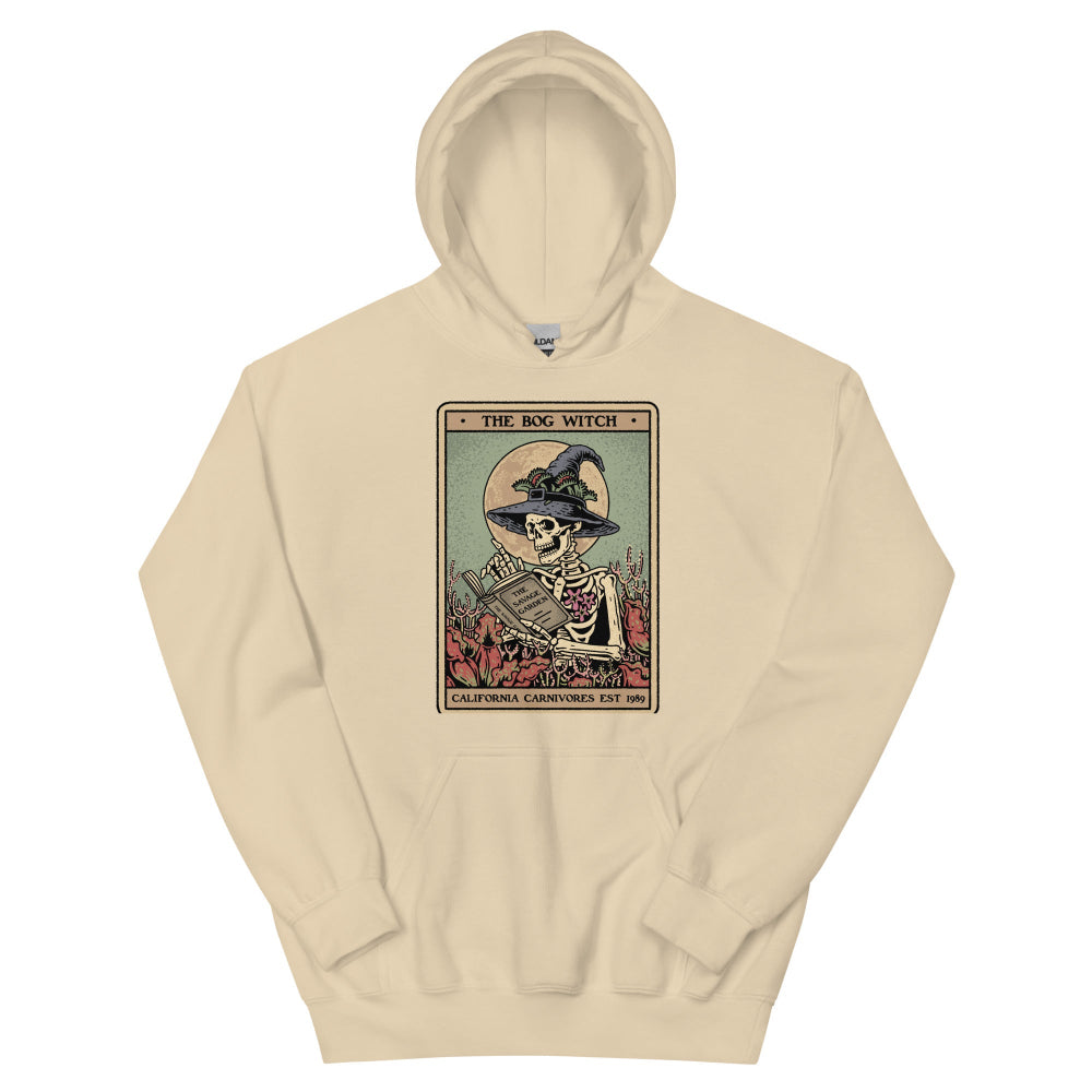 Beige hoodie with a graphic design of a skeleton in a witch hat and book on a white background
