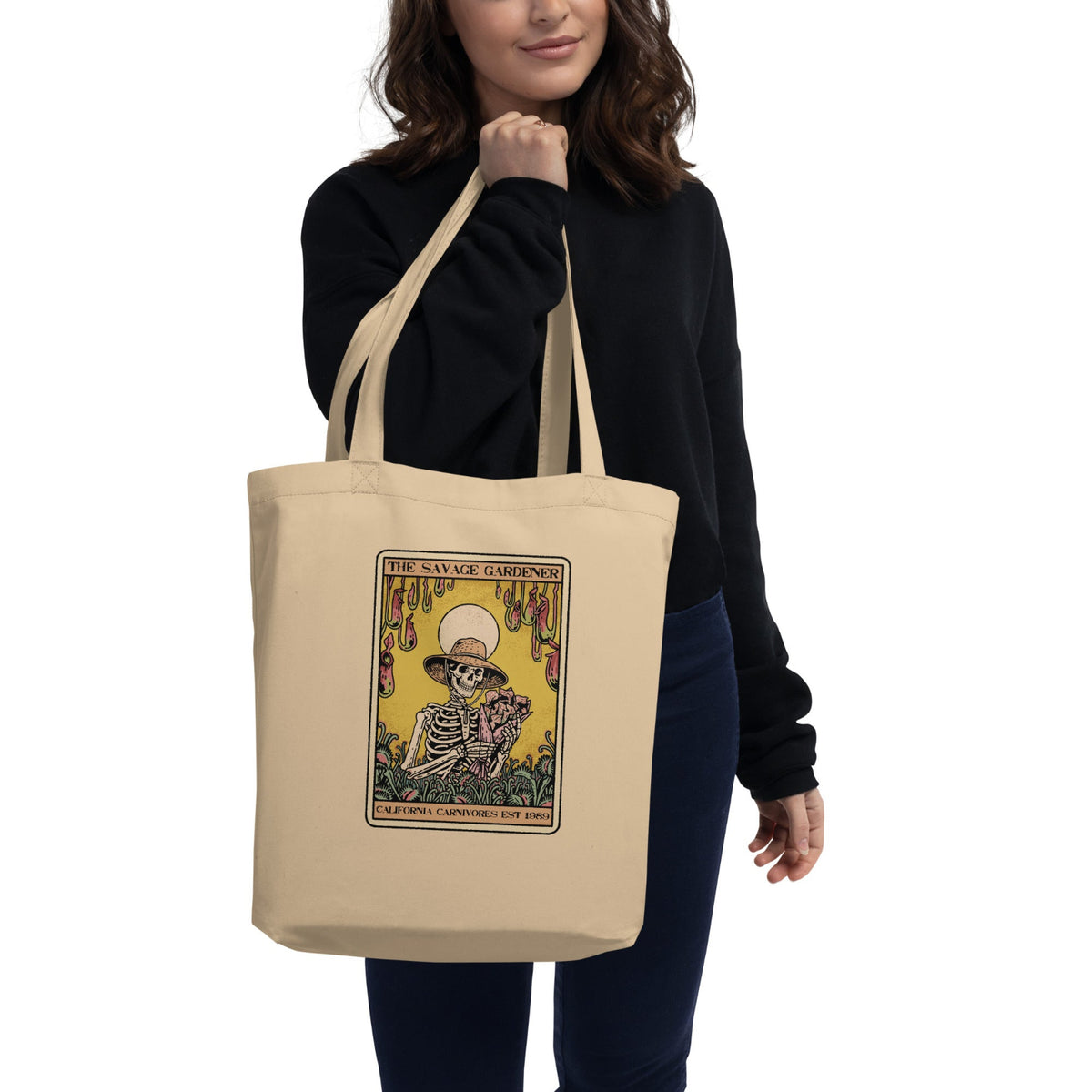 Person holding a beige tote bag with a graphic design on a white background