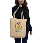 Person holding a beige tote bag with a colorful skull design and text.