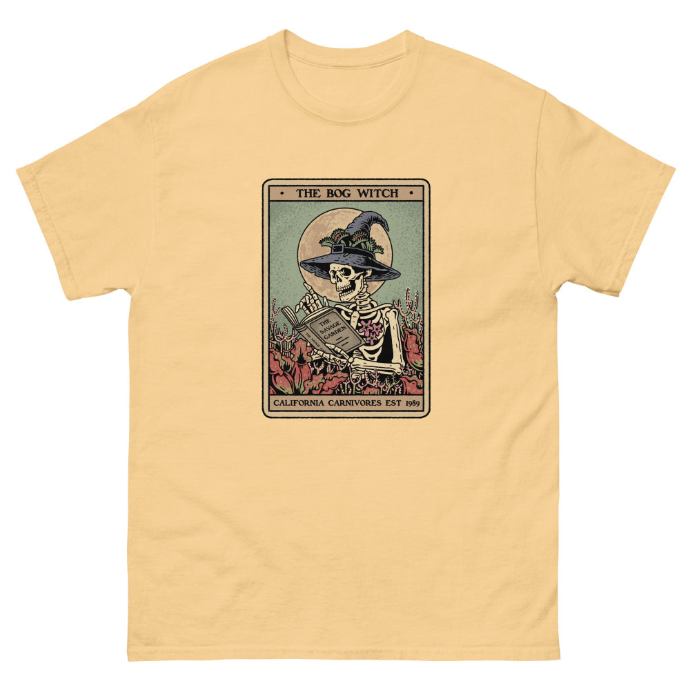 Yellow t-shirt with a graphic of a skeleton in a witch hat and cape, sitting on a card titled 'The Bog Witch'.